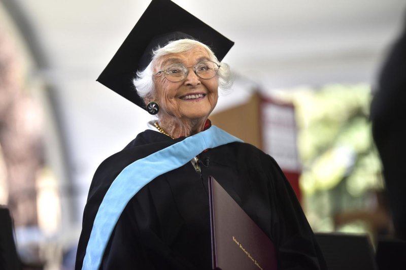 An older lady smiling big wearing a Graduation Cap and Gown