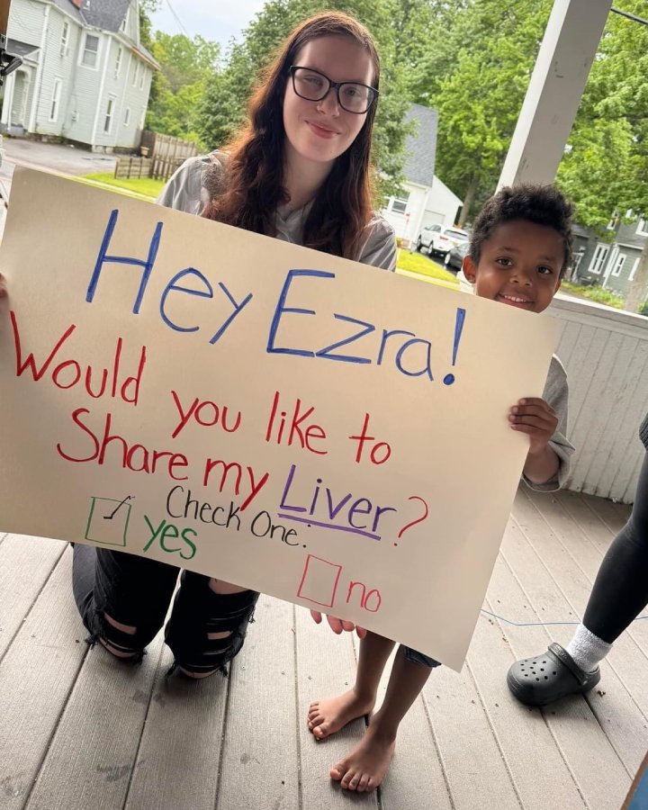 A student and teacher standing by eachother. The teacher is holding up a sign that says "Do you want to share my Liver
