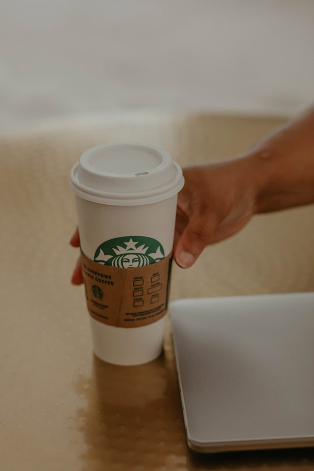 Someone reaching for a Starbucks coffee