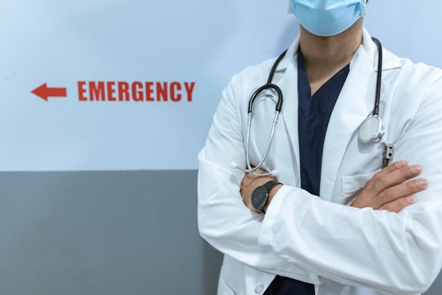 A doctor standing by a sign that says Emergency