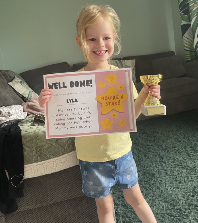 A little girl holding a trophy and a certificate