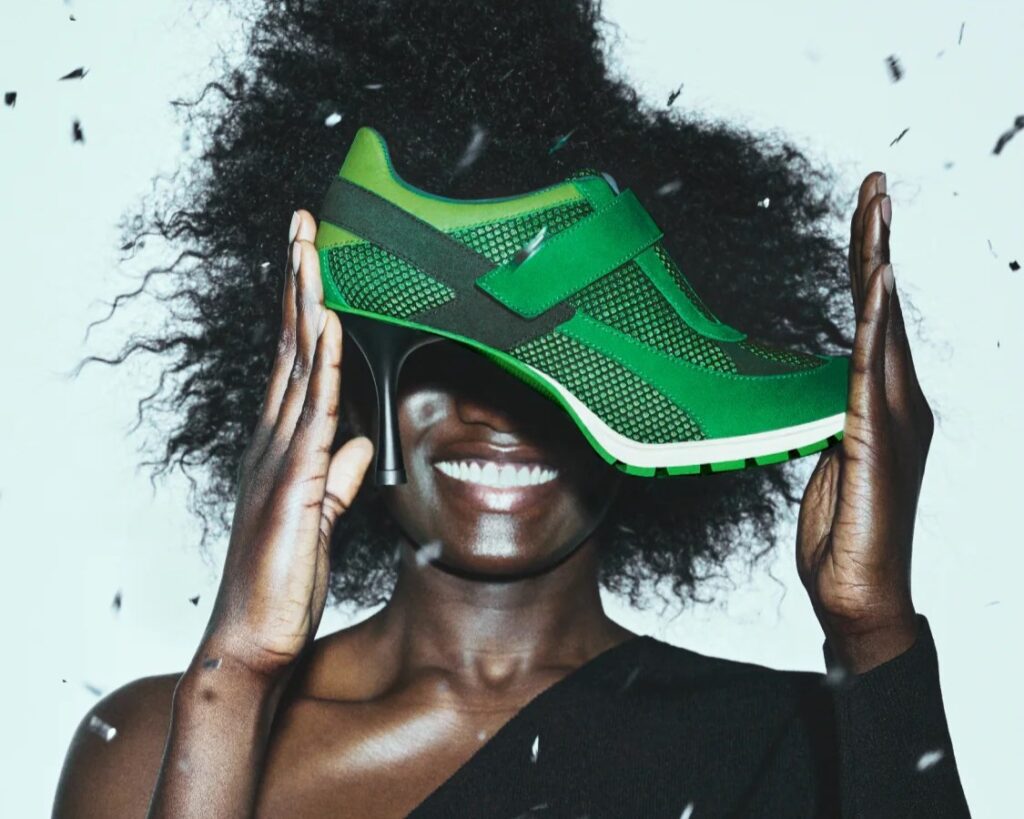 Someone holding a sneaker that has a high heel attached to it